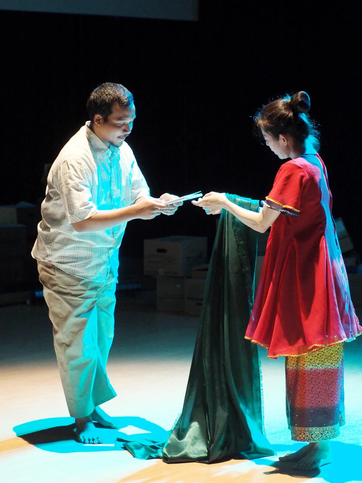 Two Lari performers face each other, holding opposite ends of a green cloth