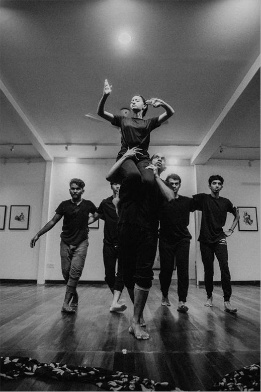 A dancer is lifted by the ensemble during a studio rehearsal